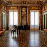 ...arricchito da un pianoforte a coda e una splendida specchiera alta quanto la parete